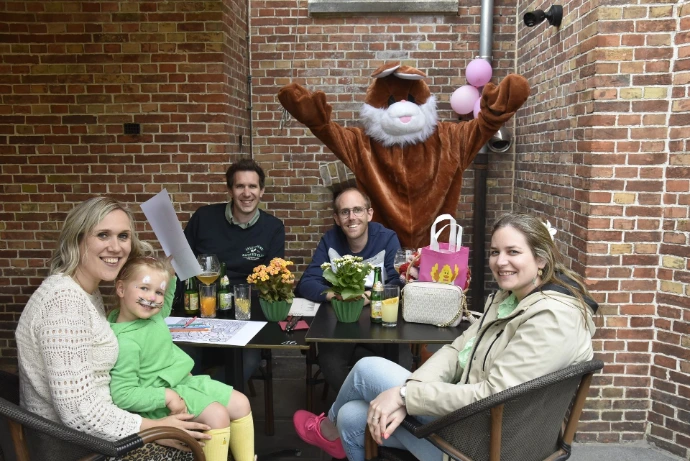 Mascotte aan tafel: De bruine haas zit gezellig bij mensen aan een picknicktafel.