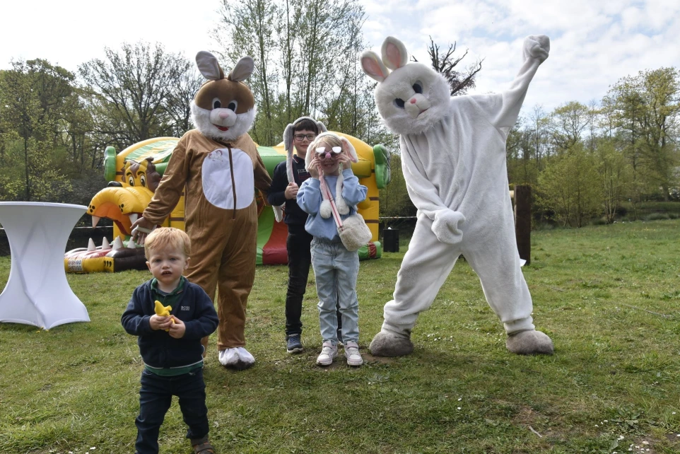 Vrolijke paashaas: De witte paashaas zwaait enthousiast naar de camera in een natuurlijke omgeving.