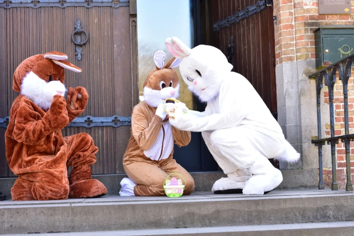 Interactie mascottes: Een bruine haas en een witte paashaas hebben een onderling onderonsje op een terras.