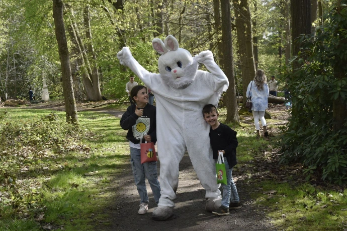 Wandeling in het bos: De witte paashaas wandelt samen met kinderen over een bospad.